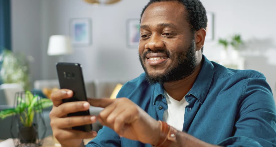 Man in his home interacting with a home security app on his smartphone